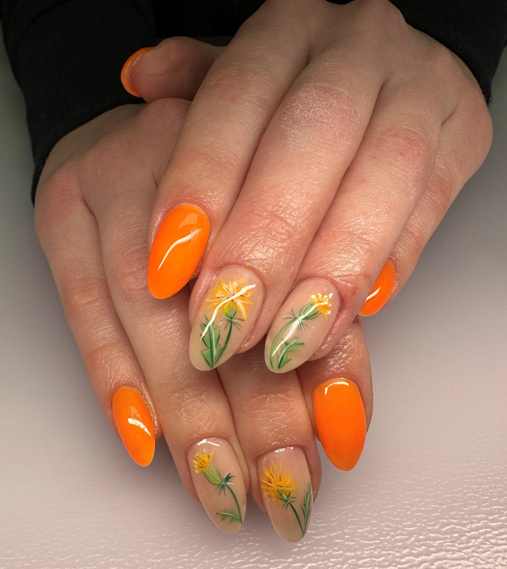Orange nails with floral nail art accents.