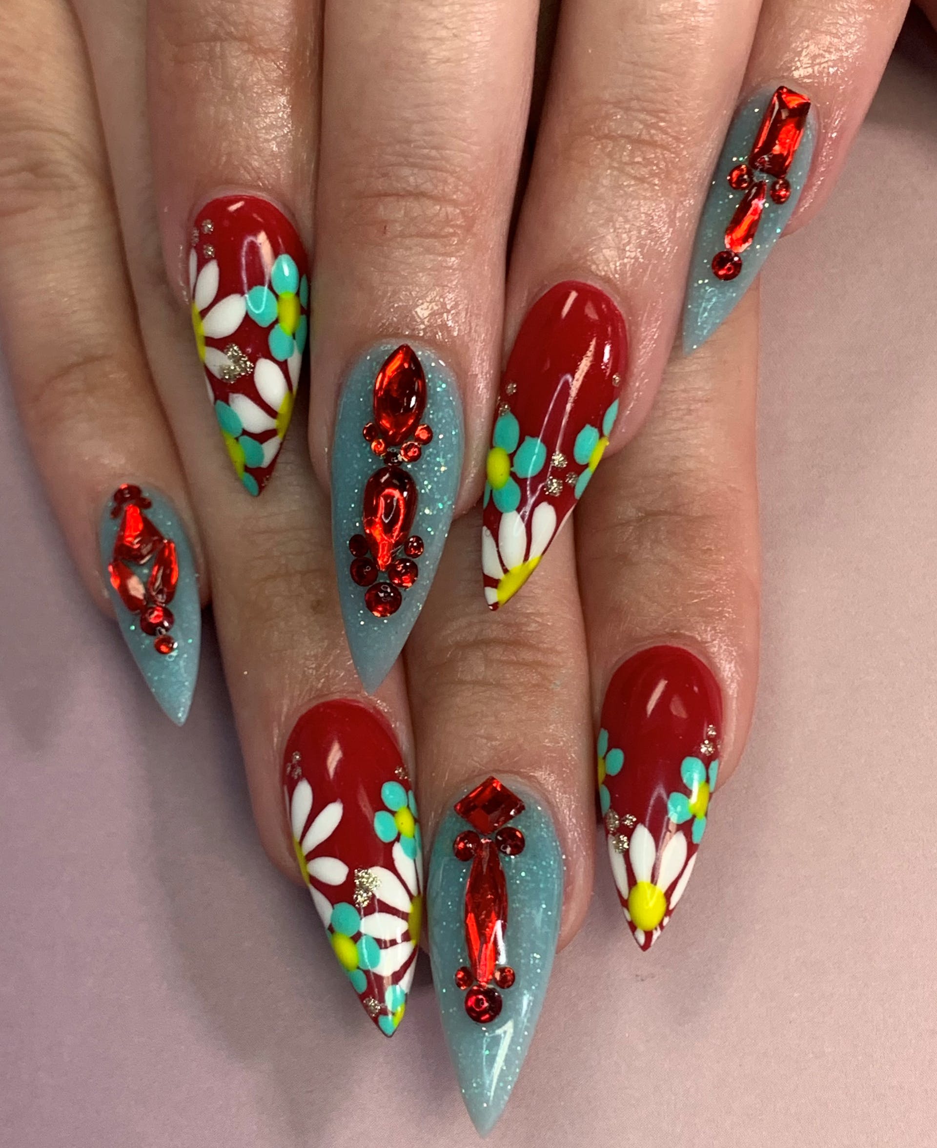 Red nails with daisy nail art and blue nails with red gems